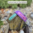 Two customised BioThane dog collars with engraved nameplates reading IGOR and PHOENIX, displayed on weathered wood.
