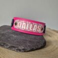 Bright pink personalised dog collar with floral printed panel reading 'DALLAS' on grey stone and wooden surface.