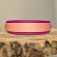 Pink and magenta handmade BioThane dog collar displayed on natural wood surface, showcasing vibrant colour combination and quality craftsmanship.
