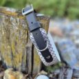 Handmade BioThane hound collar in grey with printed detail and silver hardware, displayed on weathered wood.