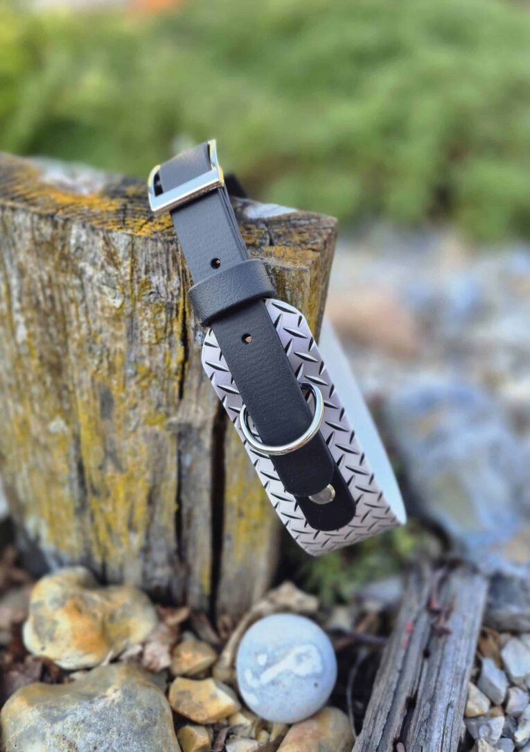 Handmade BioThane hound collar in grey with printed detail and silver hardware, displayed on weathered wood.