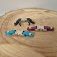 Three biothane quick release buckles in black, turquoise, and burgundy BioThane, displayed on wood.