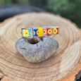 Sunflower rainbow handmade BioThane dog collar displayed on stone with wood slice background.
