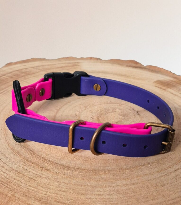 Vibrant pink and purple waterproof ecollar bungee strap with bronze hardware, displayed on natural wood.