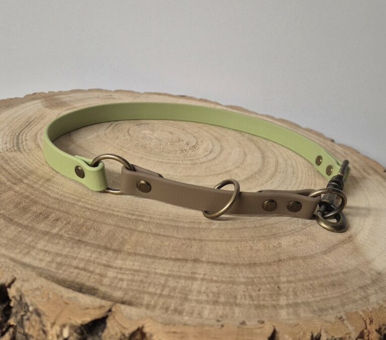 Handmade BioThane half slip dog collar in lime green and taupe with brass hardware on wood.