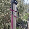 Burgundy and black BioThane handsfree lead wrapped around wooden post in garden setting