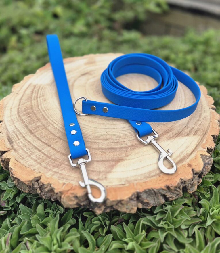 Bright blue handmade BioThane longline with traffic handle and waterproof longline lead on wooden background.