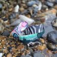 Colourful handmade BioThane dog collars displayed on pebbles, showcasing vibrant patterns and waterproof design.