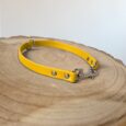 Bright yellow waterproof slip collar with metal fittings and D-ring, displayed on natural wood