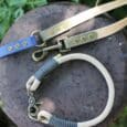 Handmade BioThane dog leads in beige, nave and olive with antique brass fittings, displayed on slate.