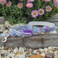 Handmade BioThane dog collars and lead set in purple butterfly print with matching hardware, displayed against pink daisies.