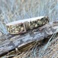 Handmade BioThane dog collar in camouflage pattern with metal buckle, displayed on weathered log.