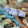 Nautical-themed handmade BioThane dog collar with blue and white maritime print, silver buckle, displayed on rope and stones.