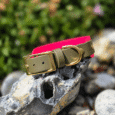 Pink and khaki handmade BioThane hound collar with brass buckle and D-ring on weathered stone.
