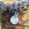 Personalised coastal-inspired BioThane collar and matching resin tag with nautical print design on sand.