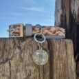 Tails of the coast biothane collar with seashell print and matching personalised resin tag displaying letter D, displayed on weathered wooden post.