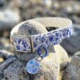 Handmade BioThane dog collar with blue nautical print design and matching ID tag on coastal rocks.