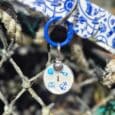 Personalised coastal-themed dog tag with initial 'I' and anchor motif, hanging from blue ring on matching nautical printed BioThane collar.