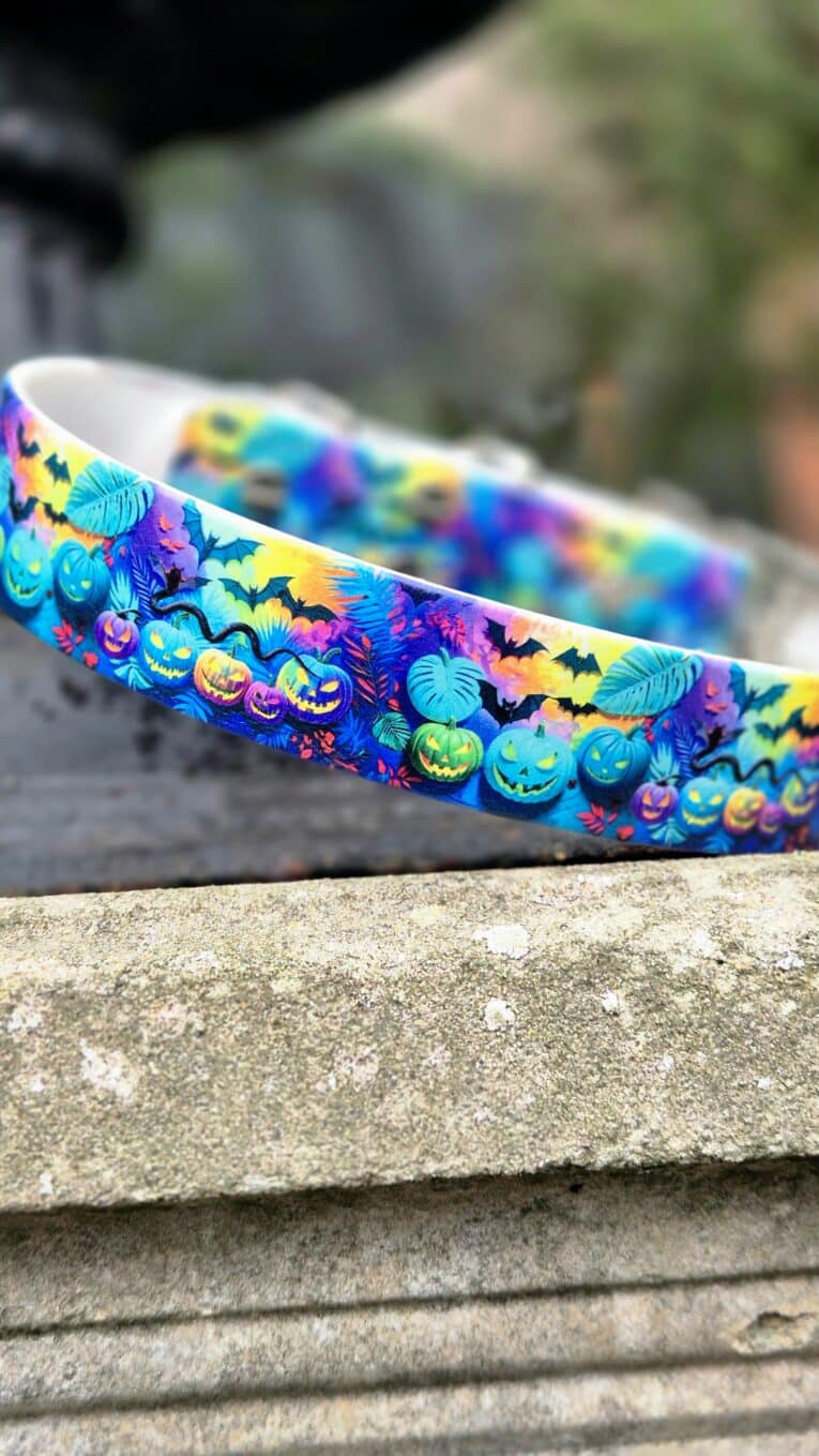 Vibrant Halloween-themed handmade BioThane dog collar featuring jack-o'-lanterns, bats, and autumn leaves in bold colours.