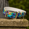 Vibrant handmade BioThane dog collar with Halloween pumpkin print design, metal buckle and D-ring, displayed on stone.